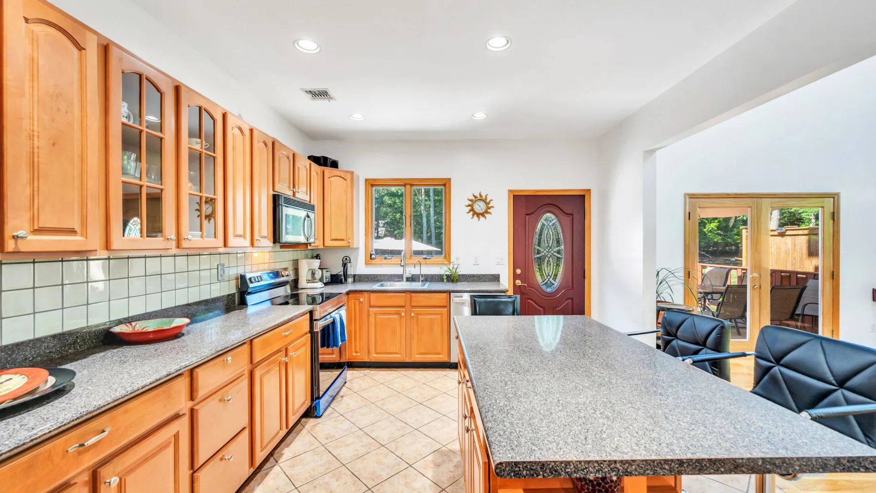 Una cocina luminosa con gabinetes de madera, salpicadero de azulejos y una isla central grande.