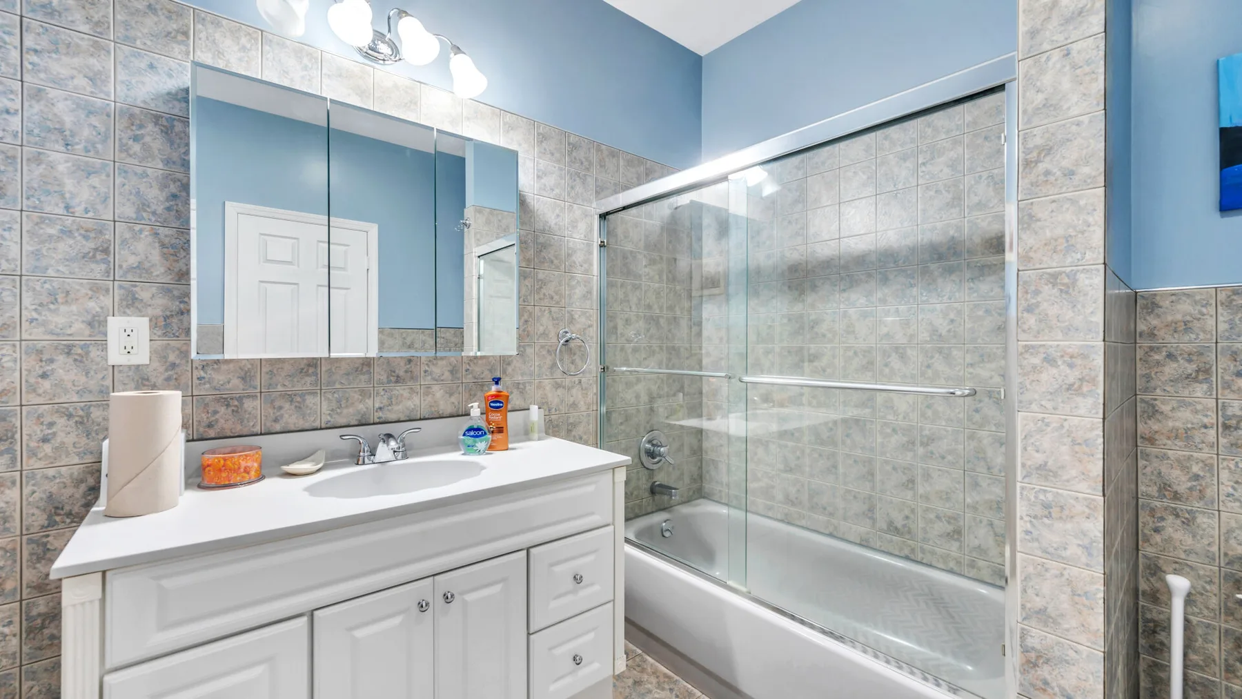 Un baño con lavabo y bañera con panel de vidrio.