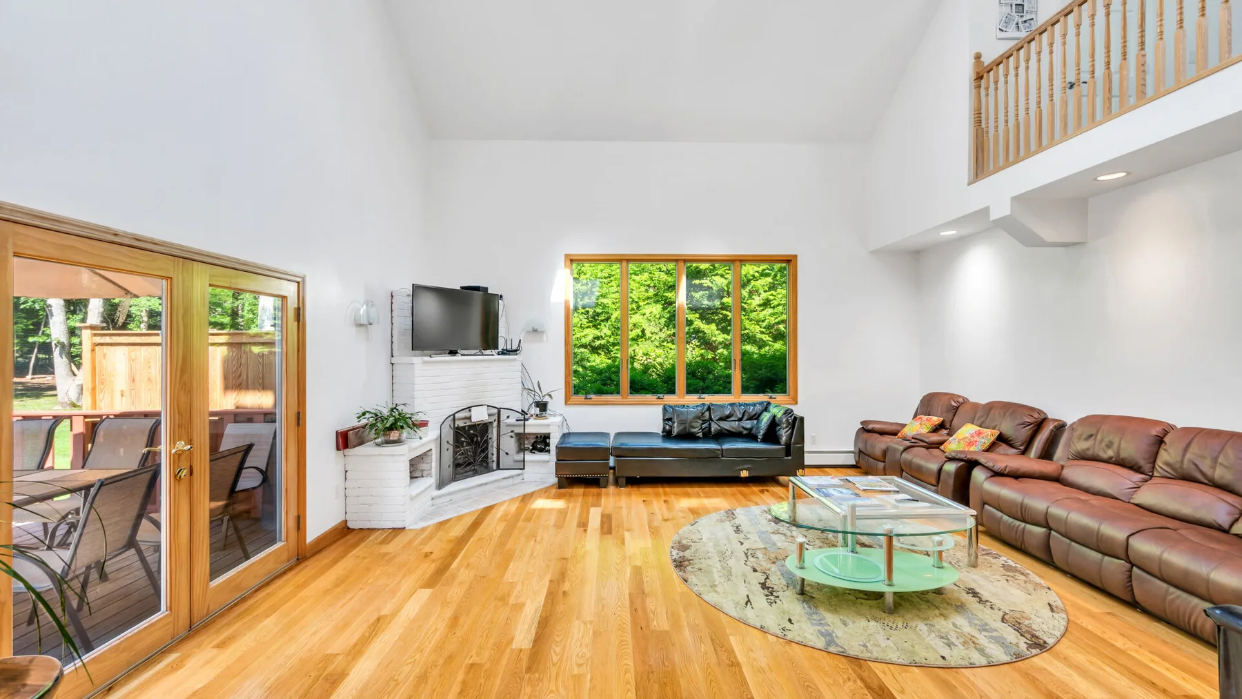 Una sala luminosa con un sofá seccional marrón y una mesa de centro de vidrio.