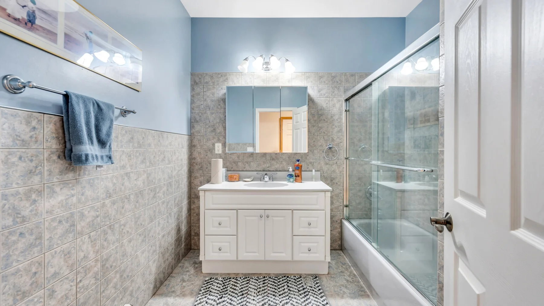 Un baño con lavabo, espejo y ducha de vidrio.