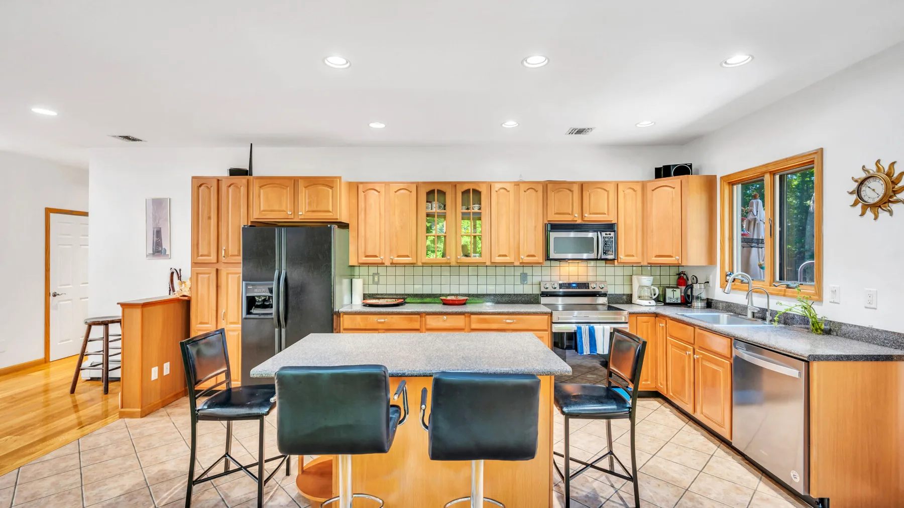 Una cocina luminosa con gabinetes de madera, electrodomésticos de acero inoxidable y una isla central.