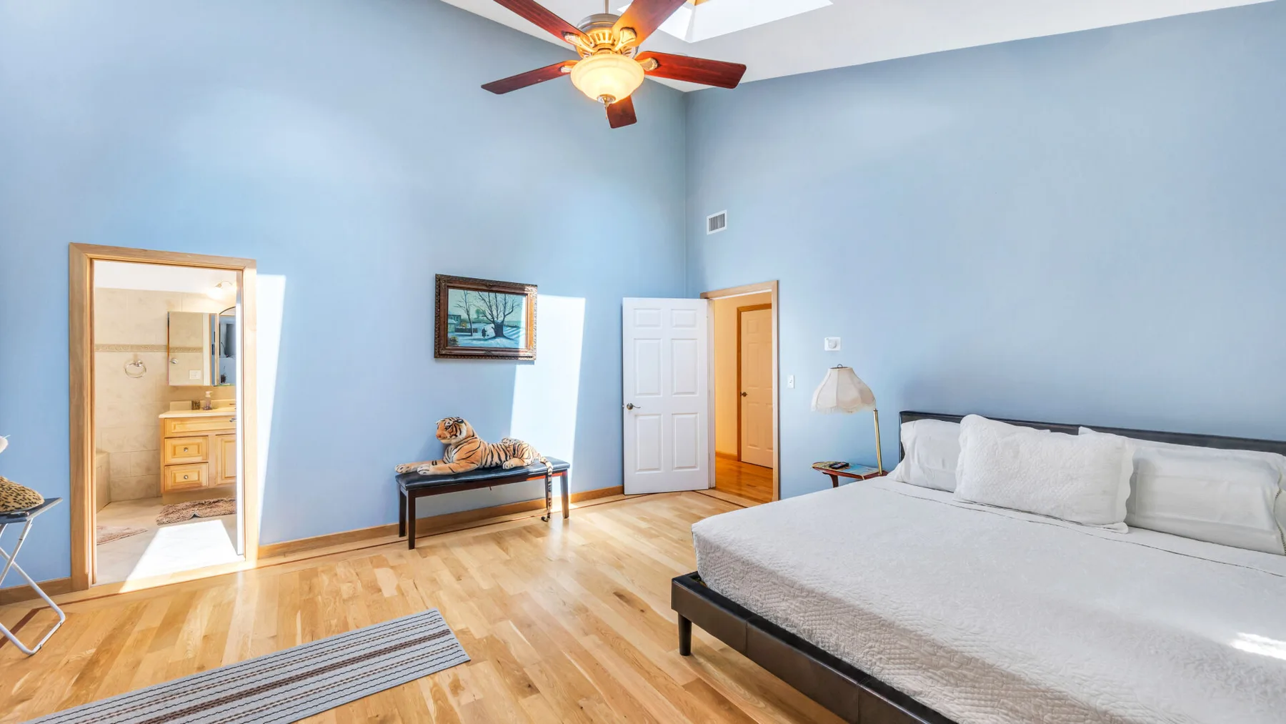 Un dormitorio con una cama grande, un ventilador de techo y una puerta abierta.
