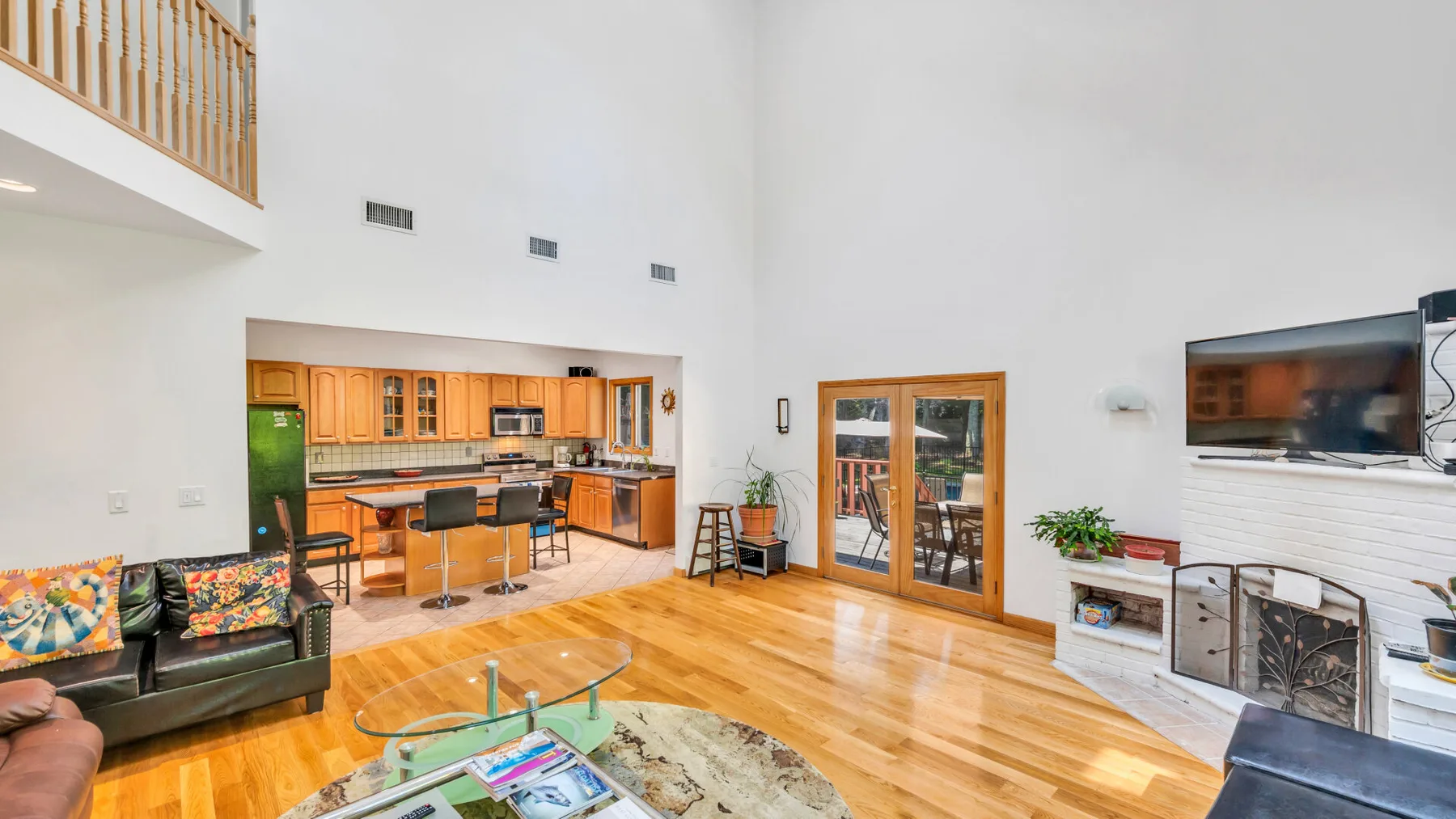 Una sala de estar luminosa y una cocina abierta, con piso de madera y ventanas amplias.