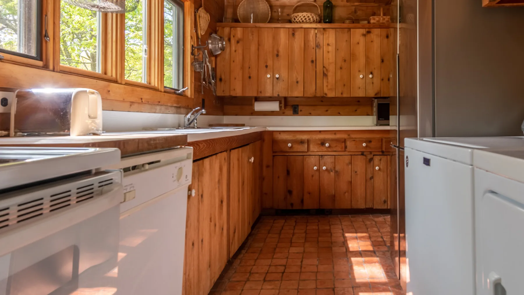 Una cocina revestida de madera con encimeras, armarios y electrodomésticos.