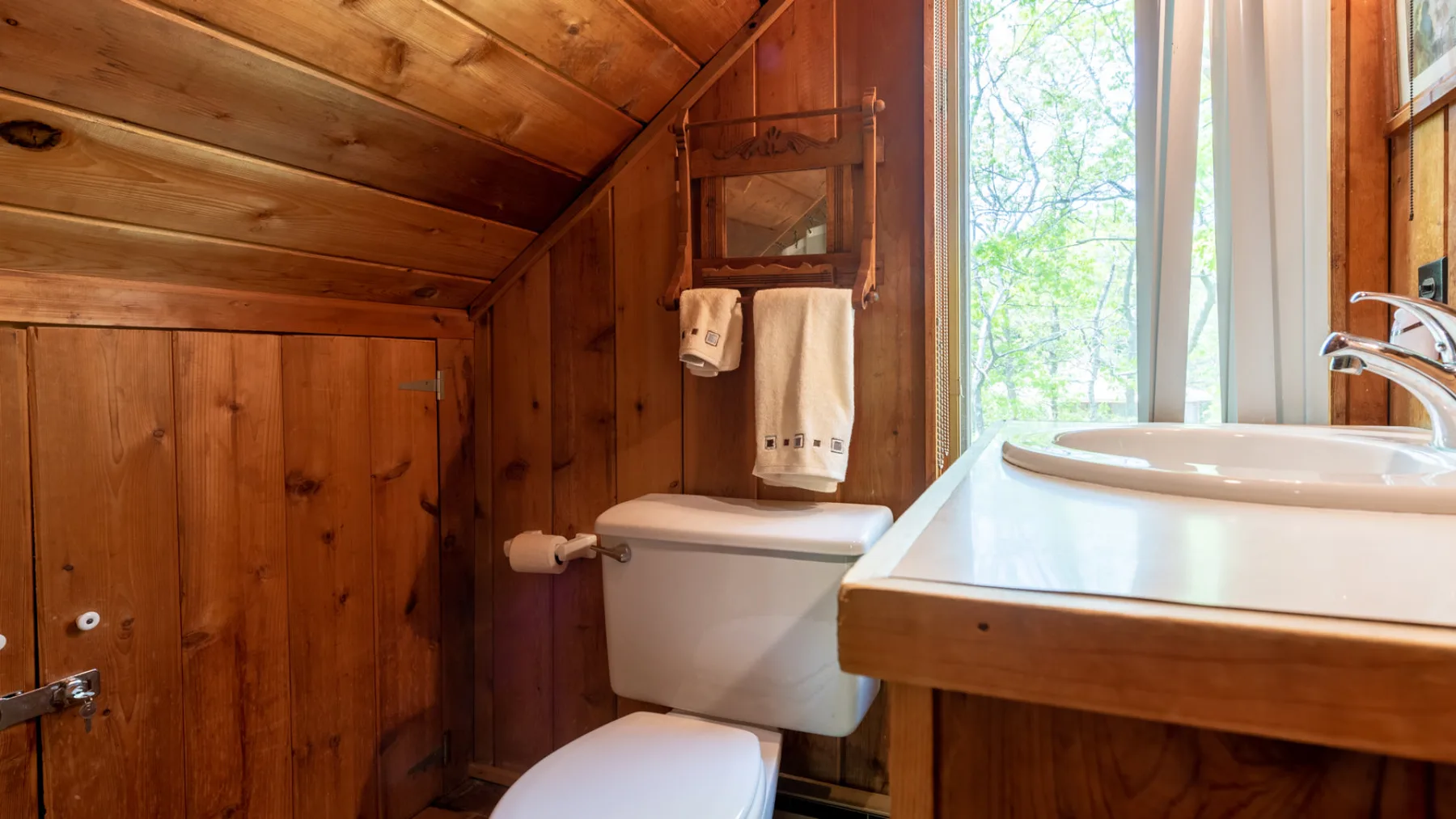 Un baño compacto con inodoro, lavabo y una ventana grande.