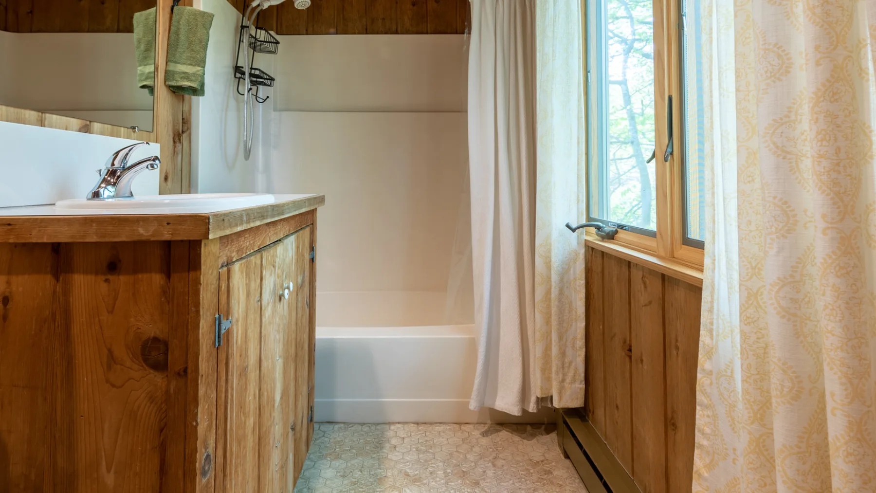Un baño con lavabo sobre un mueble de madera y una bañera detrás de una cortina.