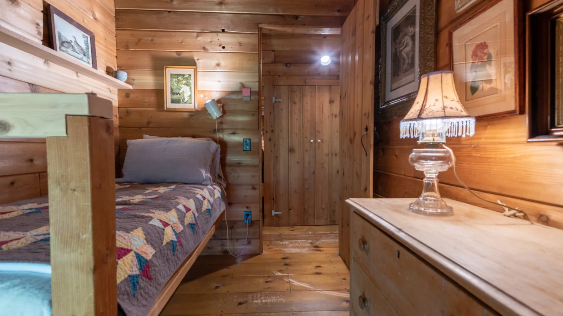 Dormitorio revestido de madera con una cama y una lámpara.