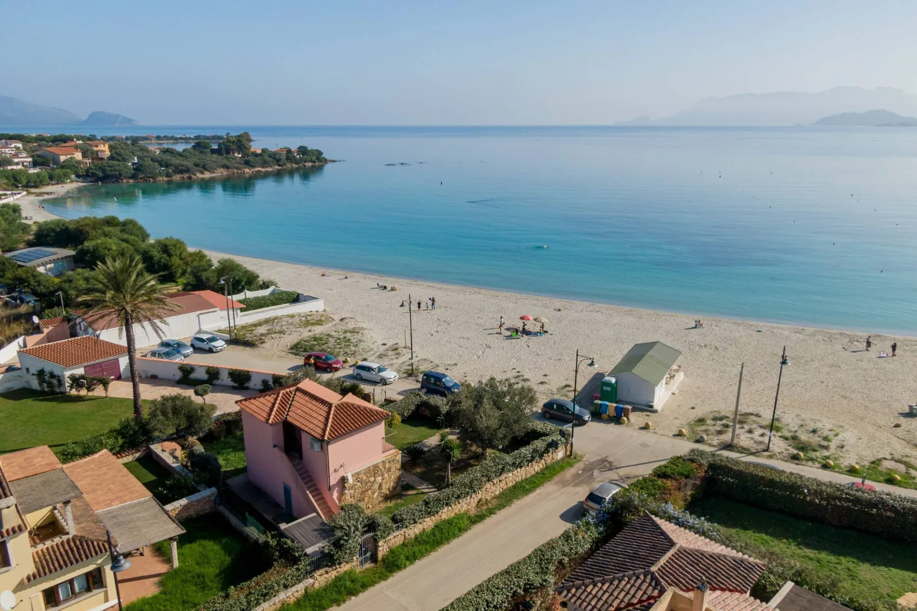 Vista aérea de una playa junto a aguas azules tranquilas y edificios costeros.