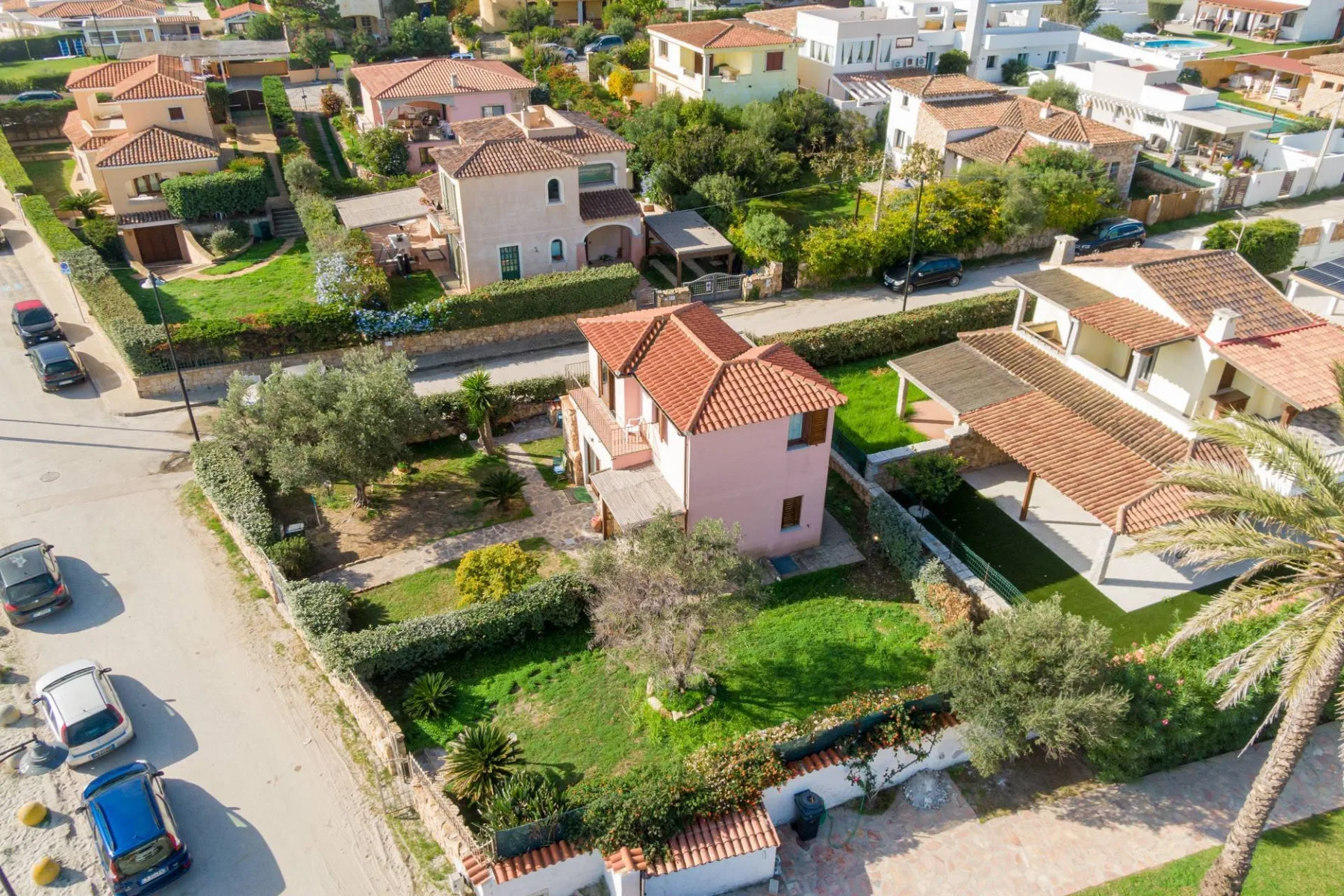 Vista aérea de un barrio residencial con casas, jardines y una calle.