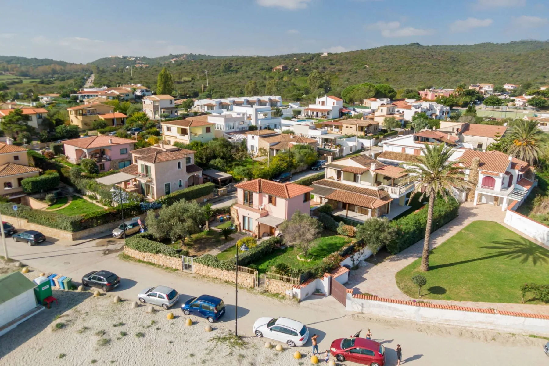 Vista aérea de un barrio residencial con casas y colinas verdes al fondo.