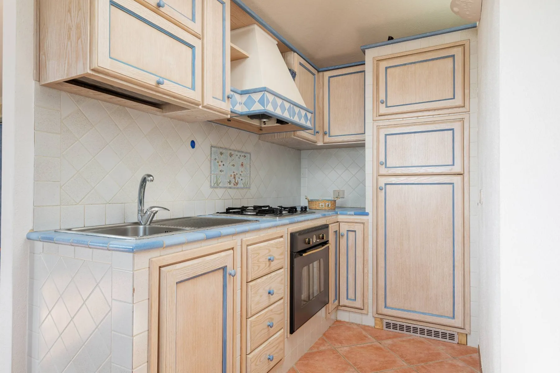 Una cocina compacta con gabinetes de madera clara, una encimera y una estufa.