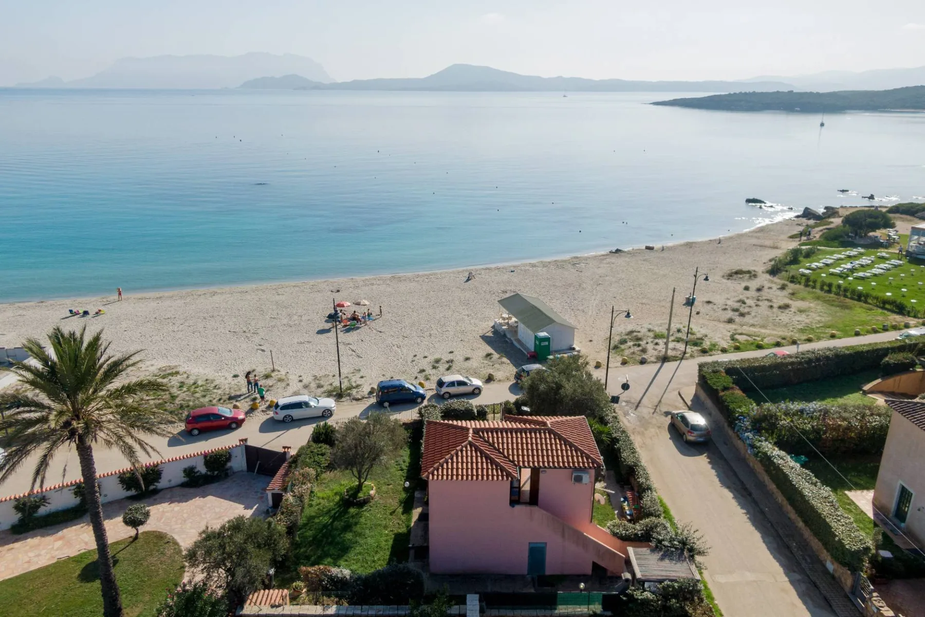 Vista aérea de una playa de arena junto a aguas tranquilas y edificios costeros.