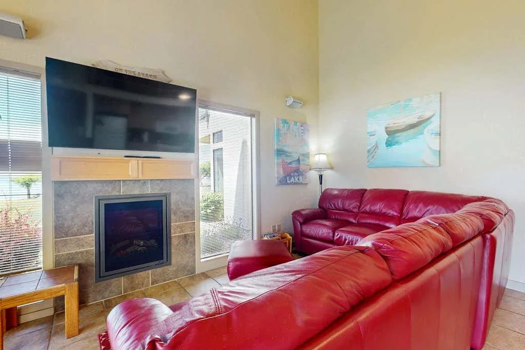 A living room with red seating facing a television and fireplace.