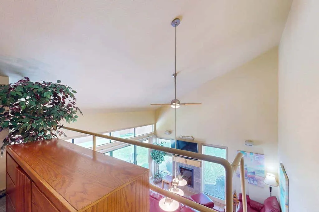 Una sala tipo loft da a una estancia luminosa con ventilador de techo y asientos.
