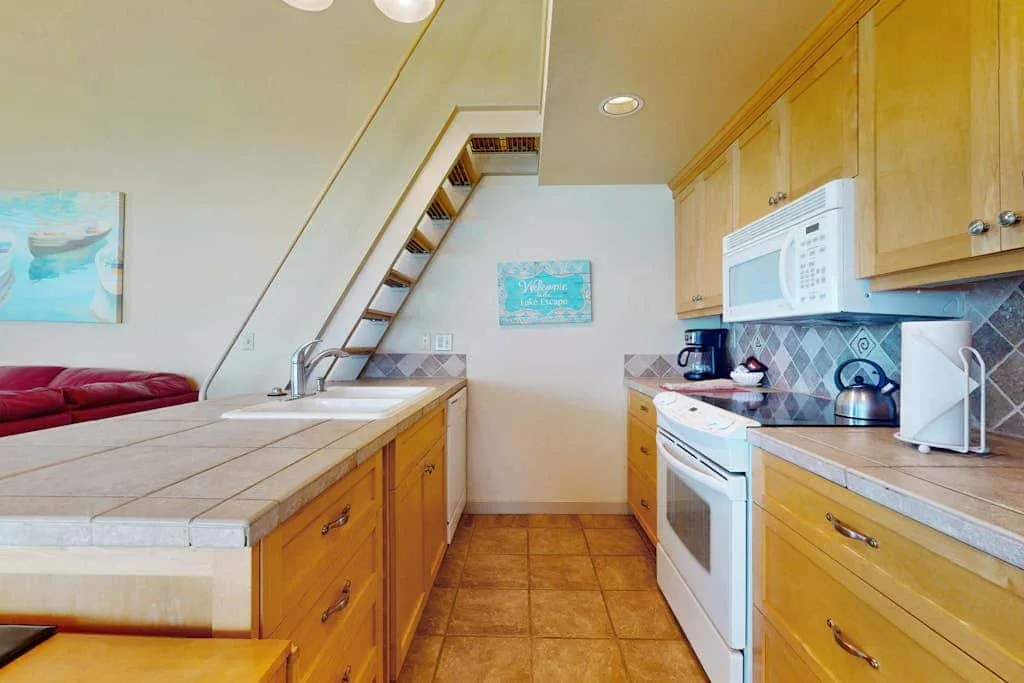 Una cocina estrecha con gabinetes de madera, encimeras de azulejos y una estufa blanca.