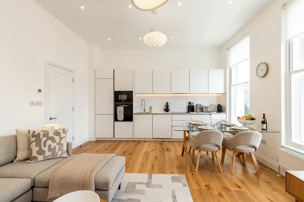 A bright open-plan kitchen and dining area with a sofa in the foreground.