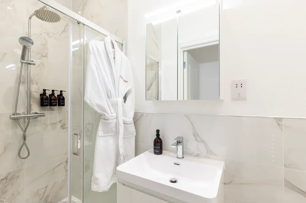 A bright bathroom with a glass shower and a white sink.