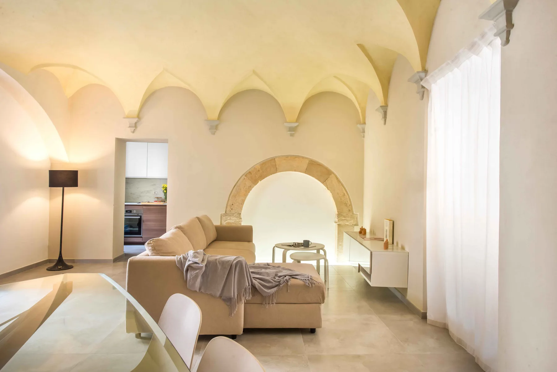 A bright living room with beige seating beneath vaulted arches.