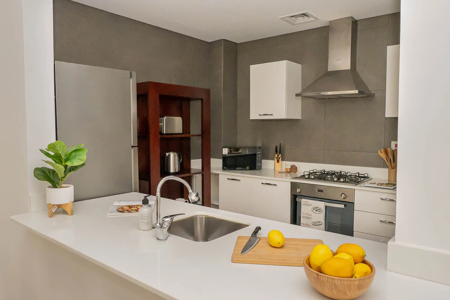 A modern kitchen with a white counter, sink, and cooking range.
