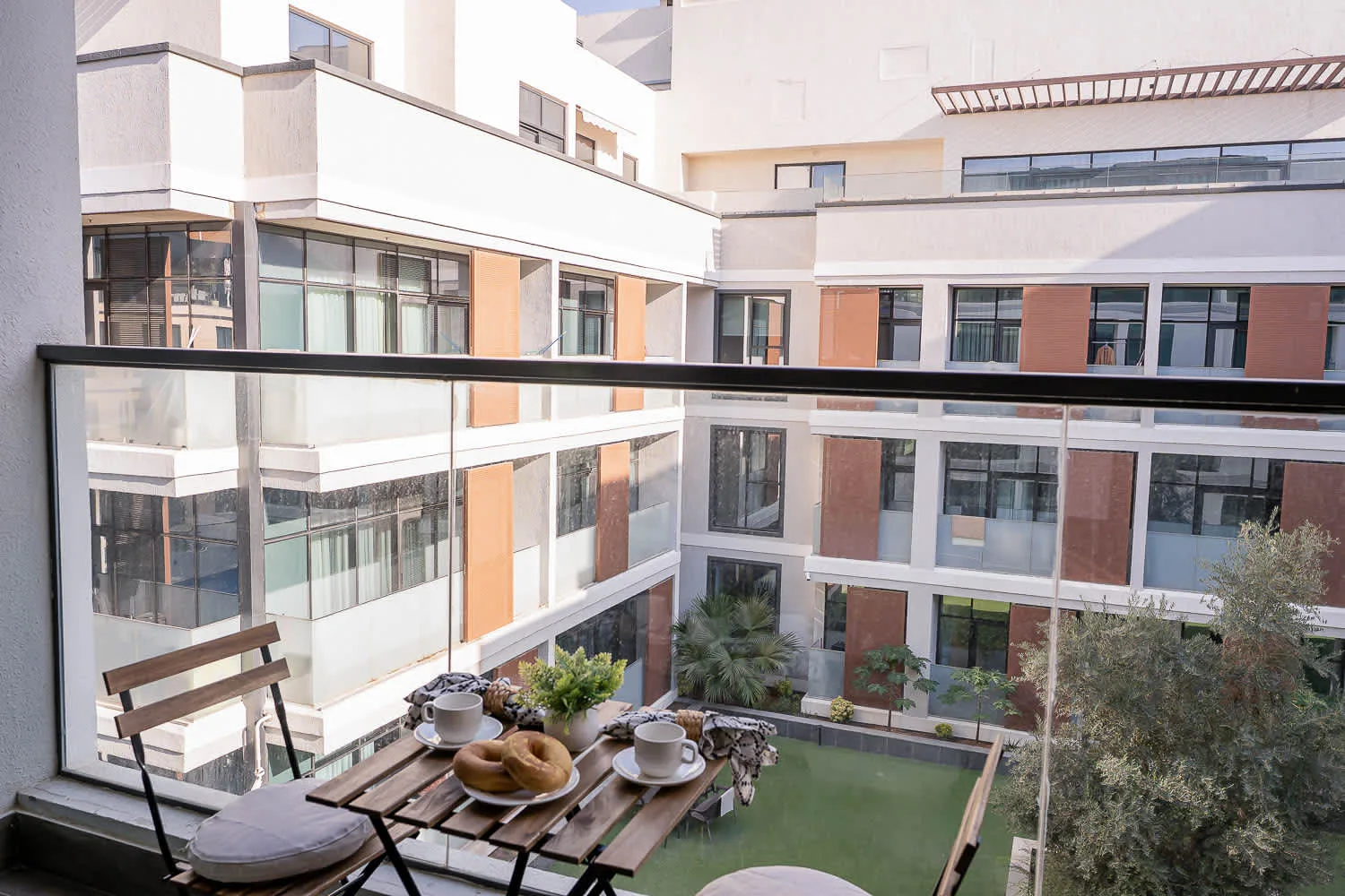 A small outdoor patio with a table and seating overlooks a landscaped courtyard.