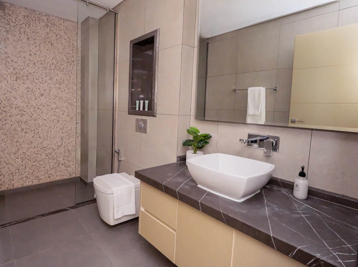 A tiled bathroom with a vanity, vessel sink, and large wall mirror.