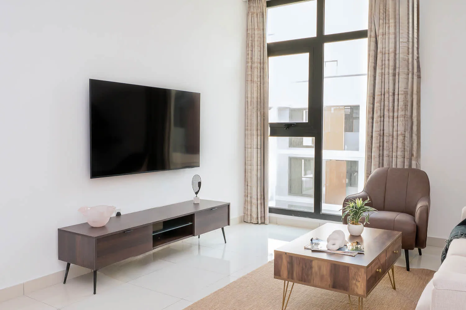 Sala de estar con televisor y una mesa de centro junto a la ventana.