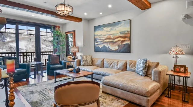 A living room with seating arranged around a coffee table and a large wall painting.