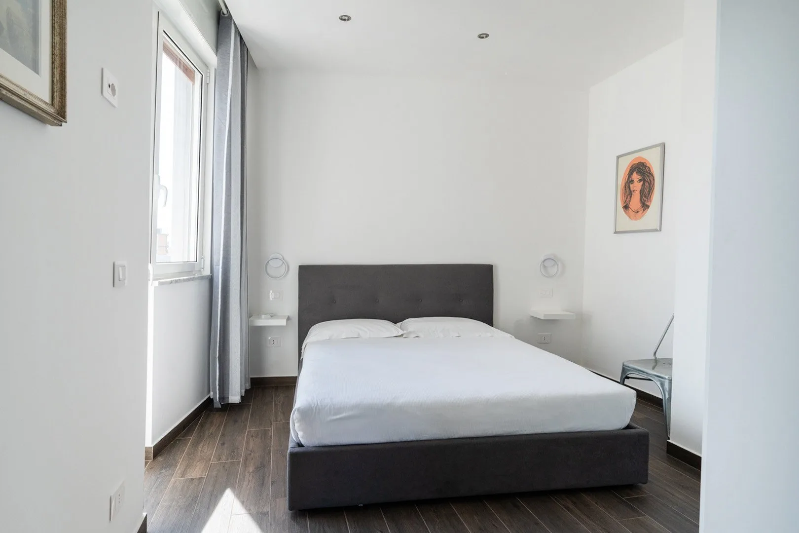 A bright bedroom with a double bed and a window beside it.