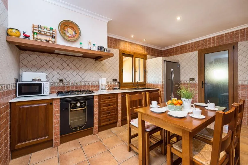 A warm kitchen and dining area with wooden cabinets and a table set with dishes.