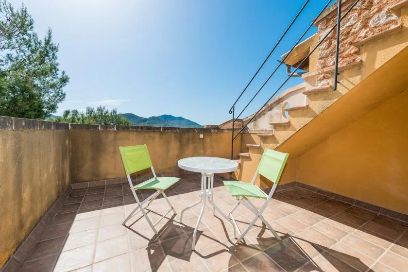 An outdoor terrace with a small table and folding chairs beside a staircase.