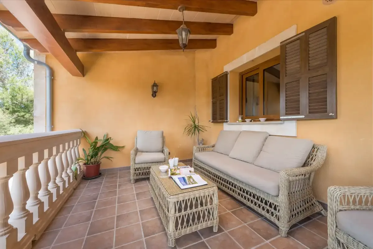 A covered patio with wicker seating and a small table.