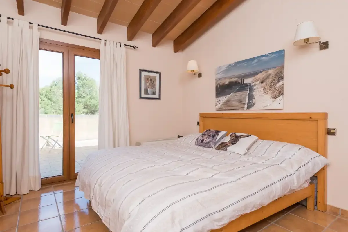 A bedroom with a double bed and glass doors opening onto a patio.