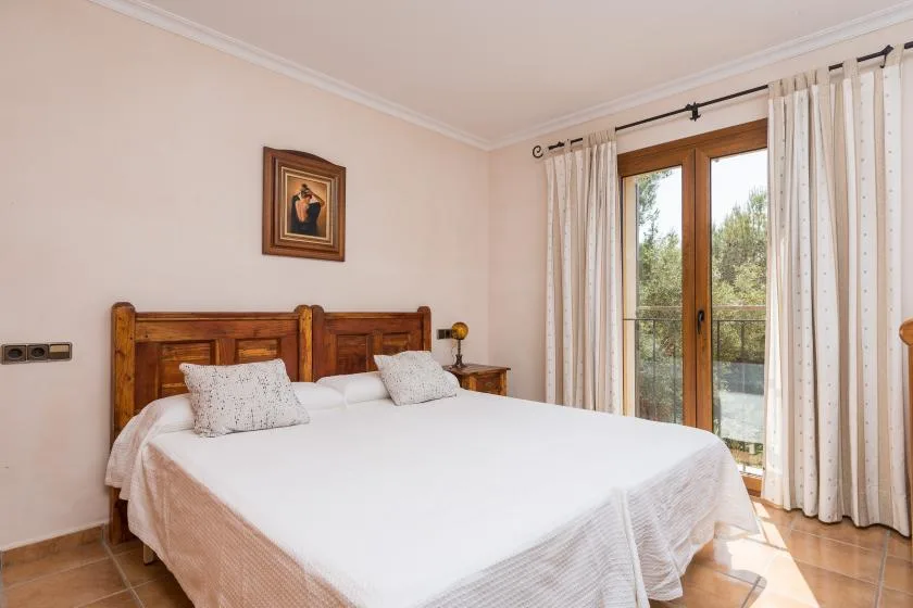 A bedroom with a wooden bed and glass doors opening onto a balcony.