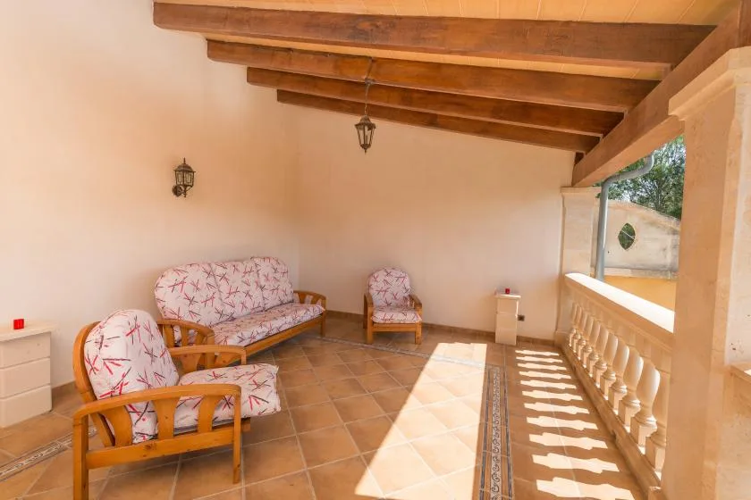 A covered terrace with cushioned seating and a tiled floor.