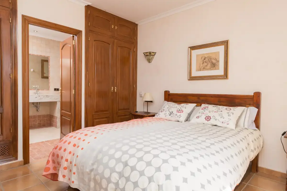 A bedroom with a wooden bed and a patterned bedspread.