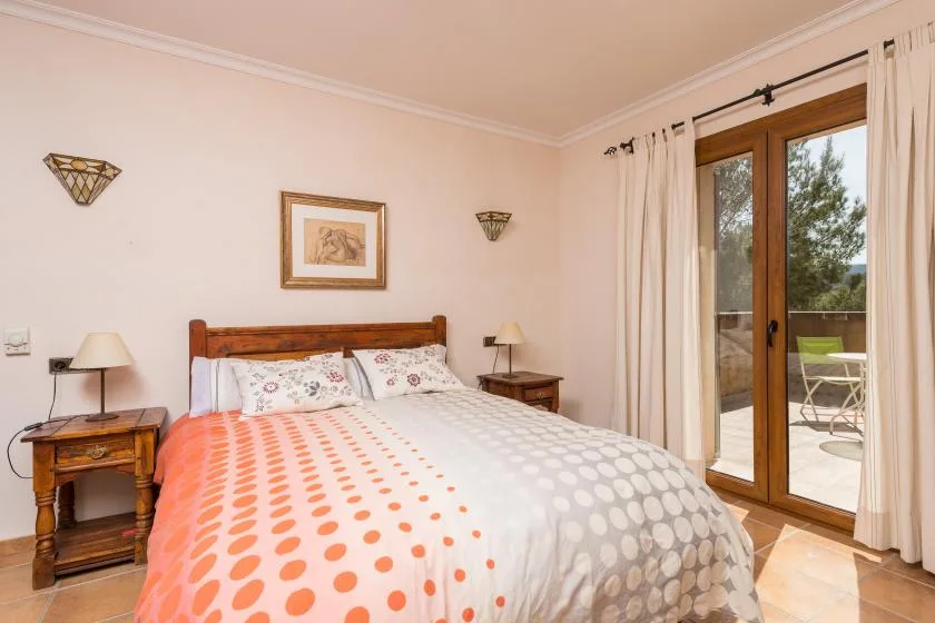 A bedroom with a wooden bed, patterned bedding, and glass doors opening onto a patio.