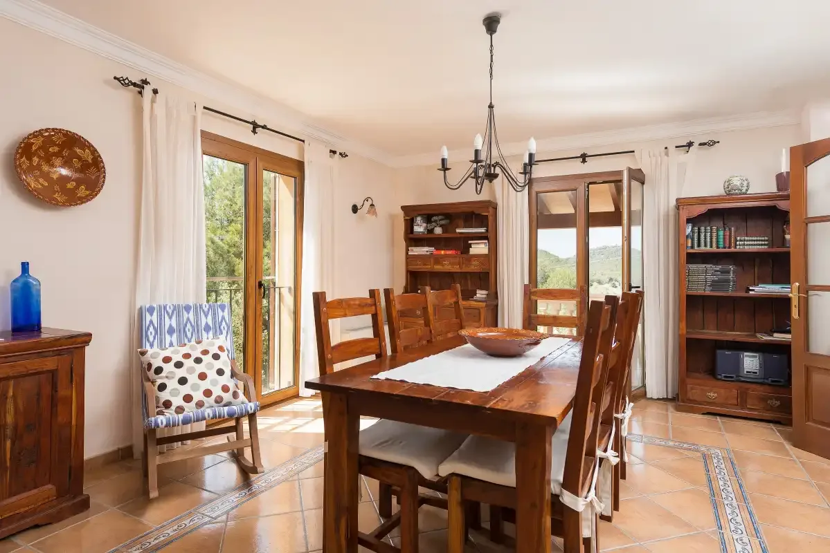 A dining room with a wooden table, chairs, and bookshelves.