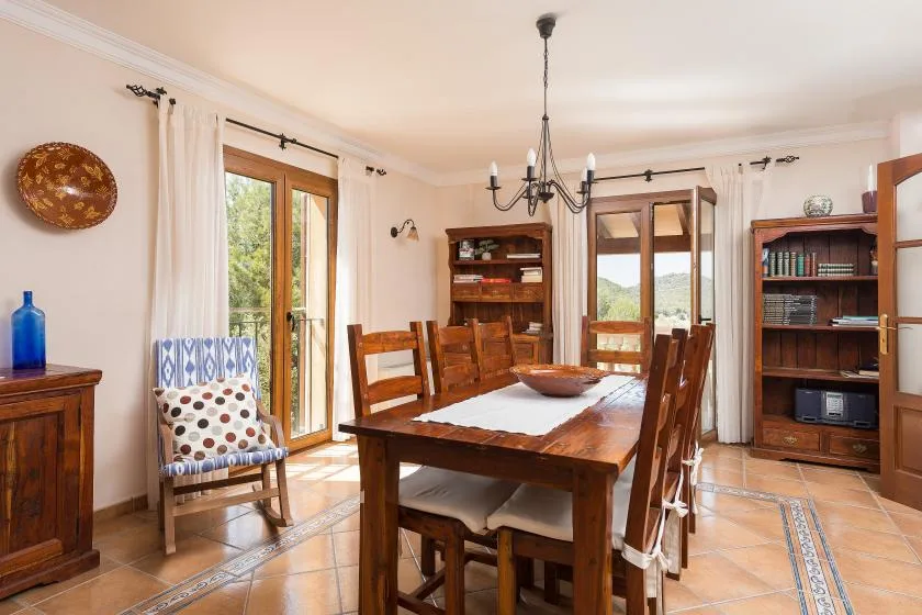 A dining room with a wooden table and chairs beside glass doors.