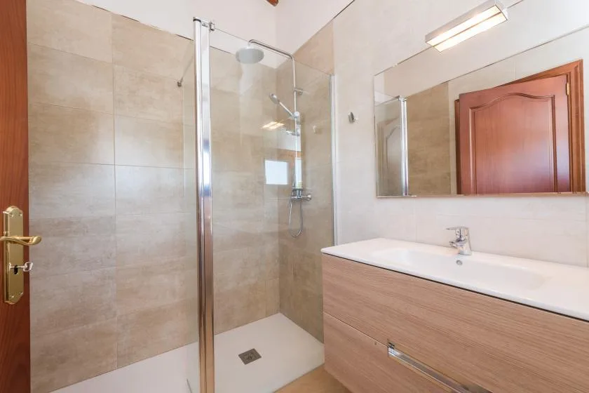 A bathroom with a glass shower and a wide sink vanity.