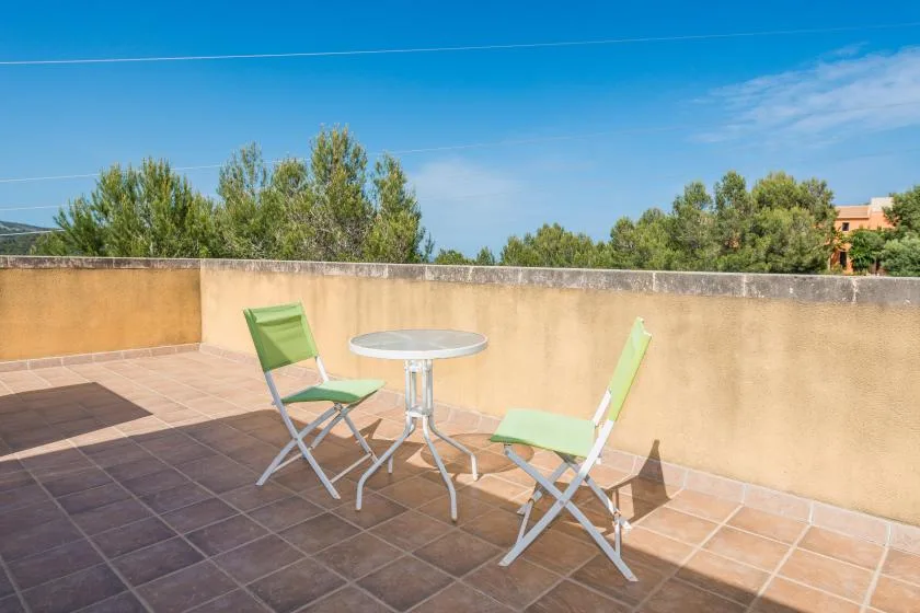 A sunny rooftop terrace with a small table and green seating.