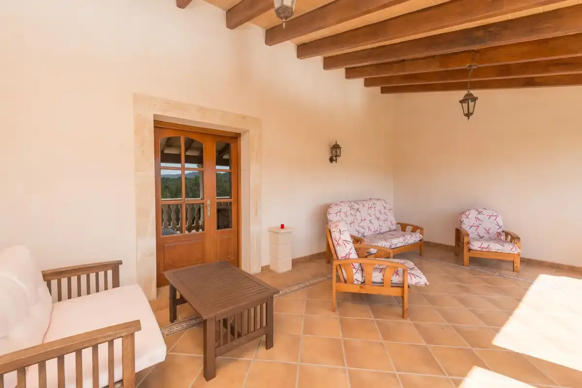 A covered patio with wooden seating, a small table, and a glass-paneled door.