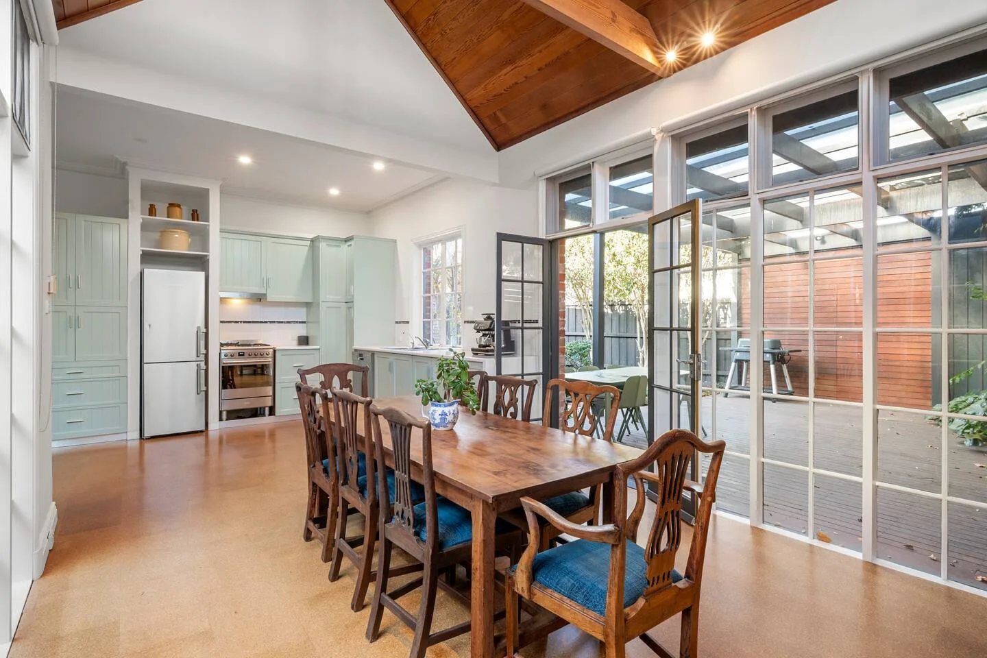 Comedor con una mesa de madera y sillas junto a grandes puertas de vidrio.