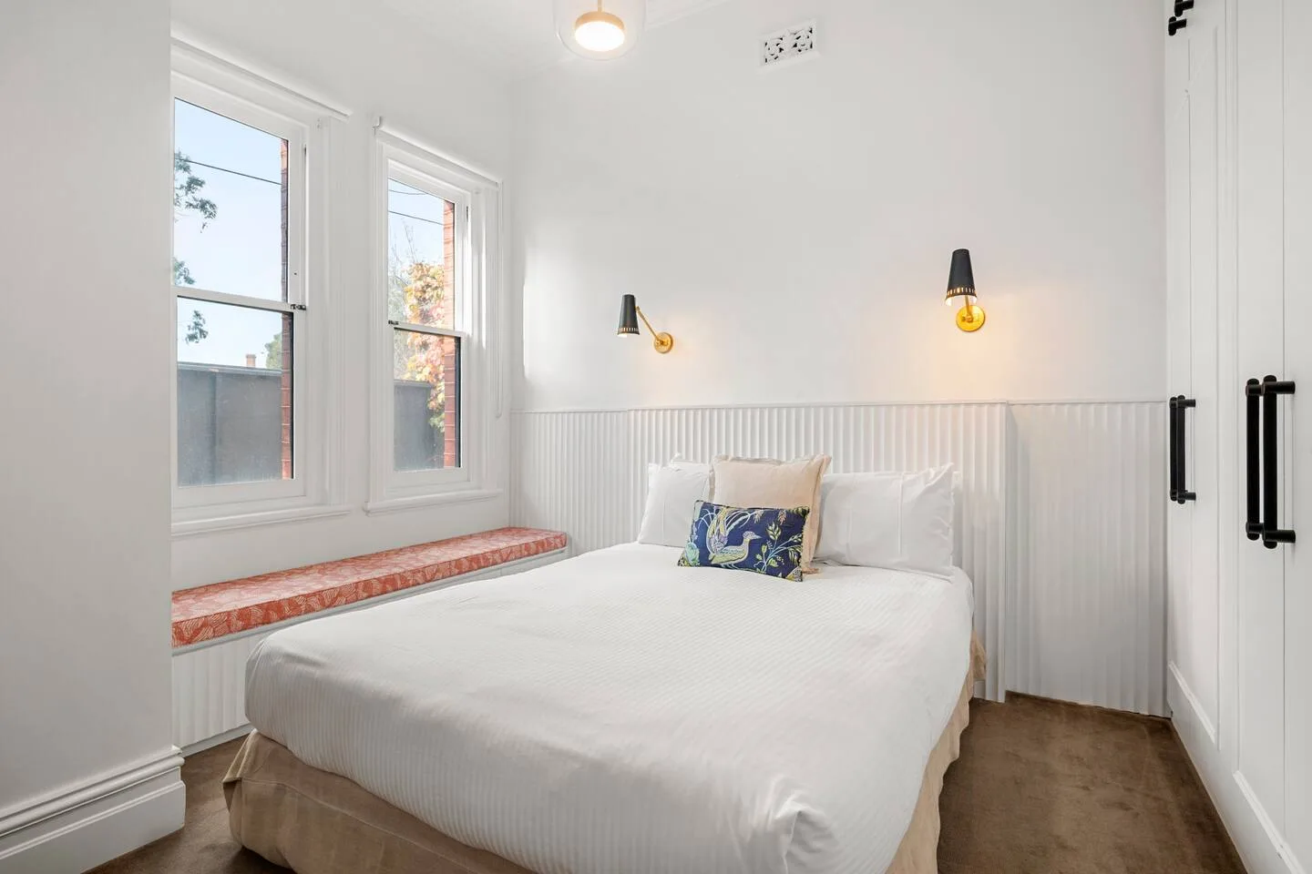 El dormitorio principal cuenta con una cama queen, armarios empotrados y elegantes apliques de pared, y ofrece un espacio tranquilo y refinado para descansar.