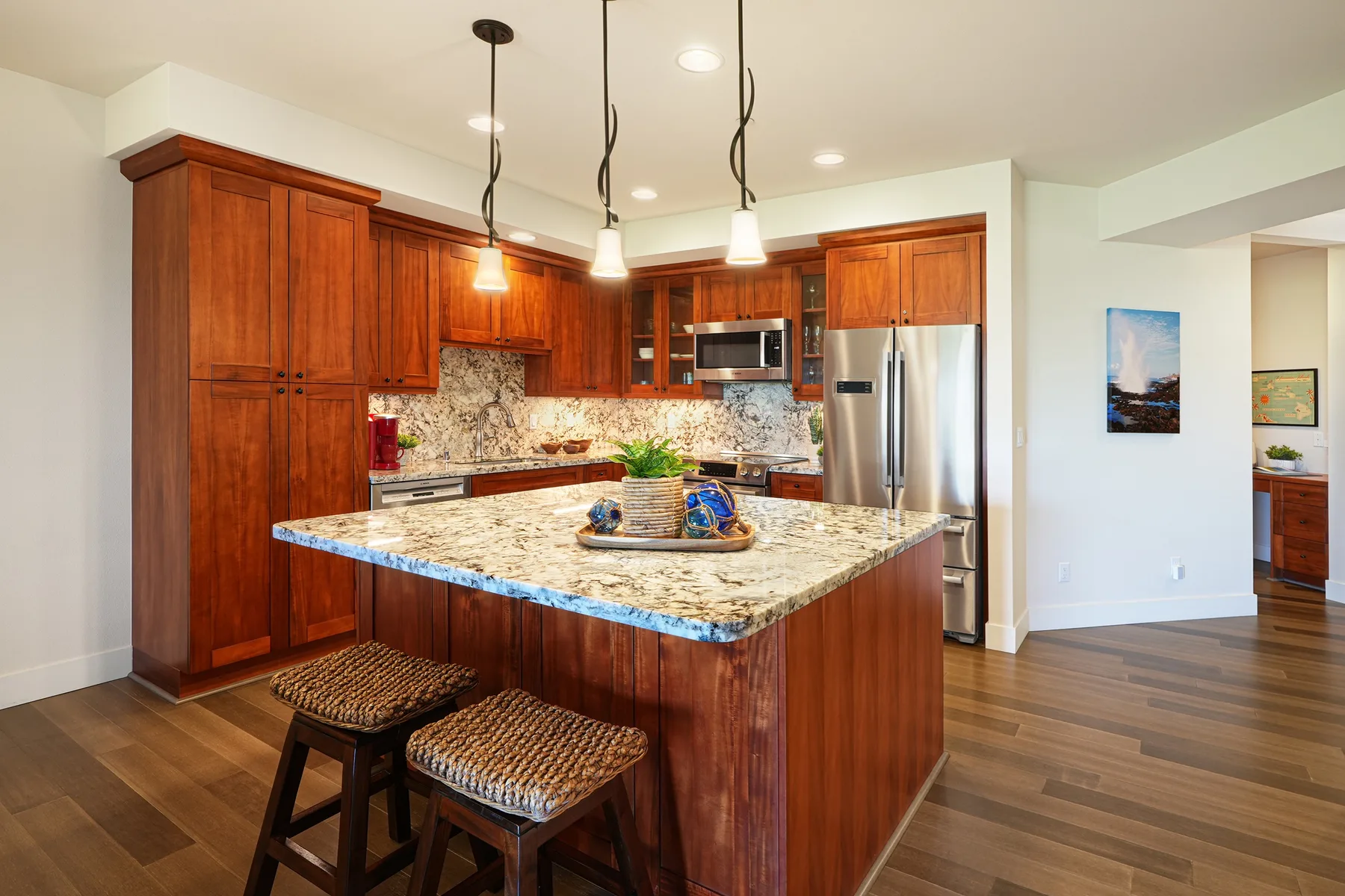 Una cocina luminosa con gabinetes de madera, una isla central y lámparas colgantes.