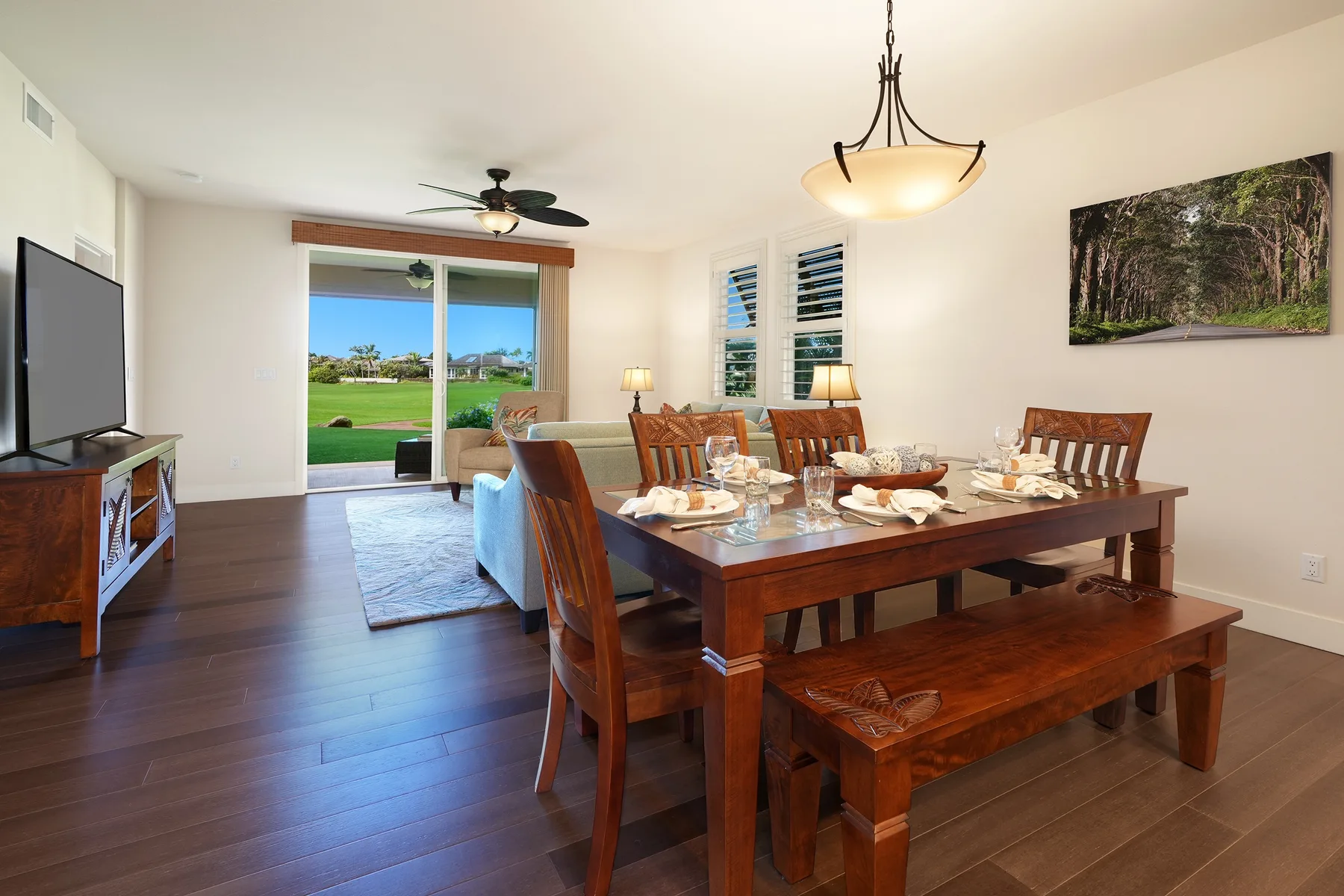 Un comedor con una mesa de madera puesta para comer junto a una sala luminosa.