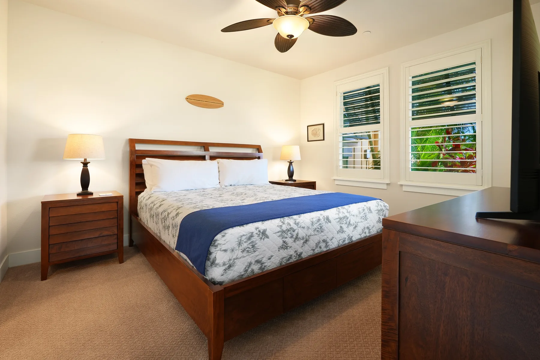 Un dormitorio con una cama de madera, mesitas de noche y dos ventanas.