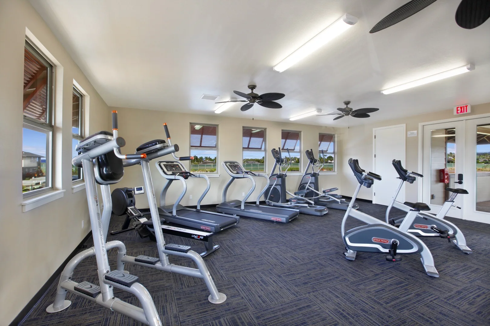 Una sala de ejercicios con varias cintas de correr y otras máquinas.