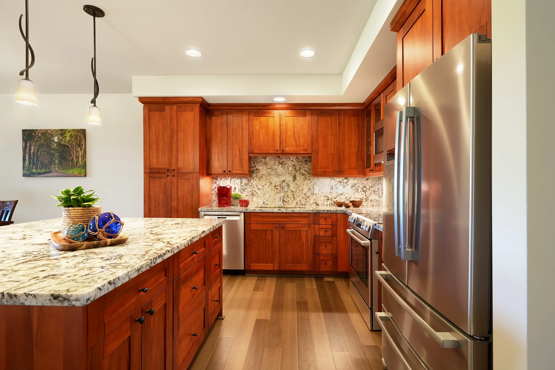 Una cocina con gabinetes de madera, encimeras de piedra y electrodomésticos de acero inoxidable.