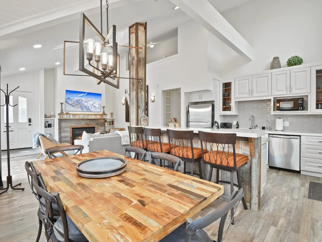 An open dining and kitchen area features a long wooden table and counter seating.