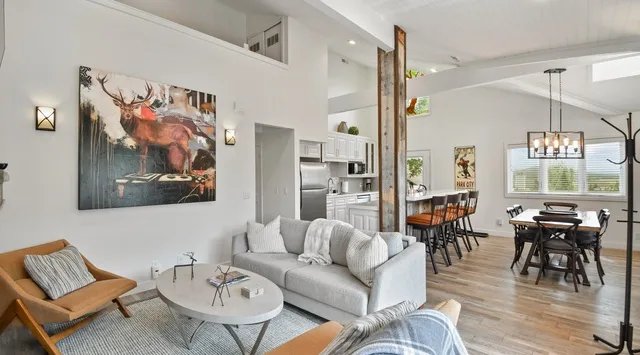 Relax in this airy open-concept living space, where modern comfort meets rustic charm with soaring ceilings, natural wood accents, and seamless flow to the dining and kitchen areas.